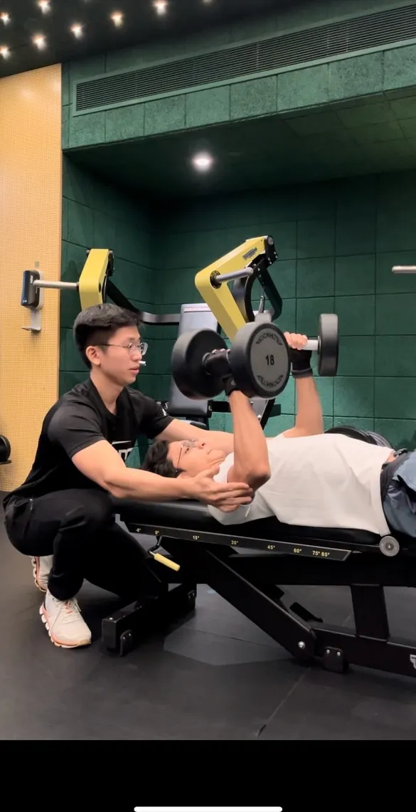 Jeremiah Lung coaching a client through a dumbbell bench press