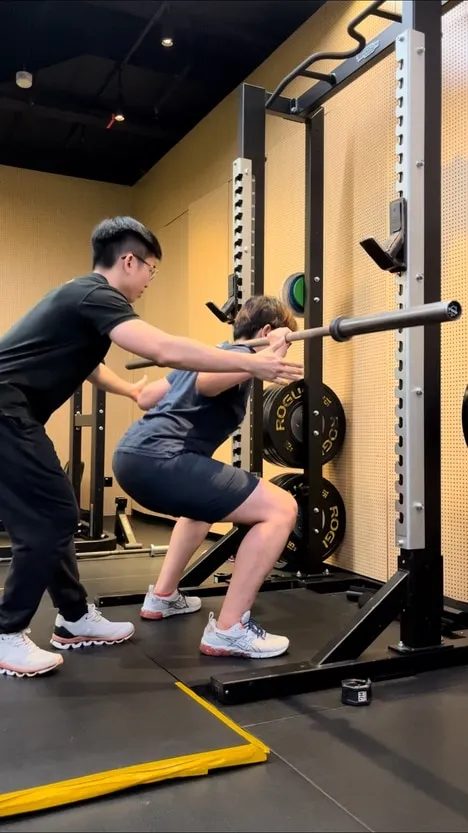 Jeremiah Lung coaching a client through a barbell squat