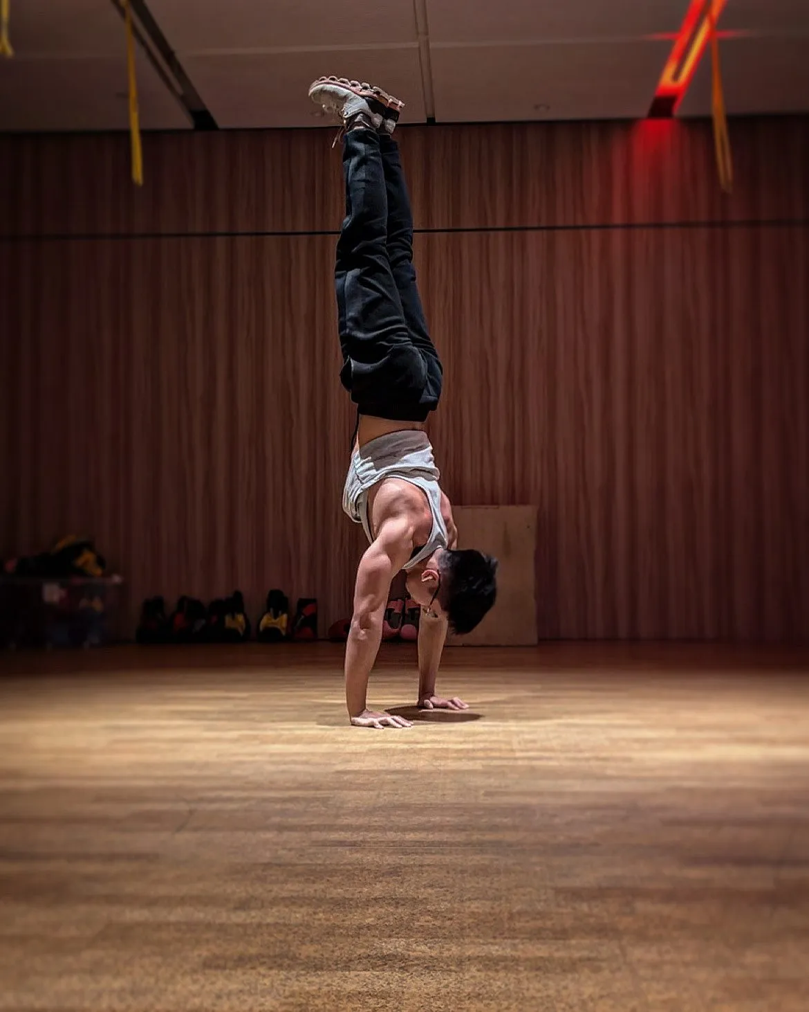 Jeremiah Lung holding a freestanding handstand on a studio floor