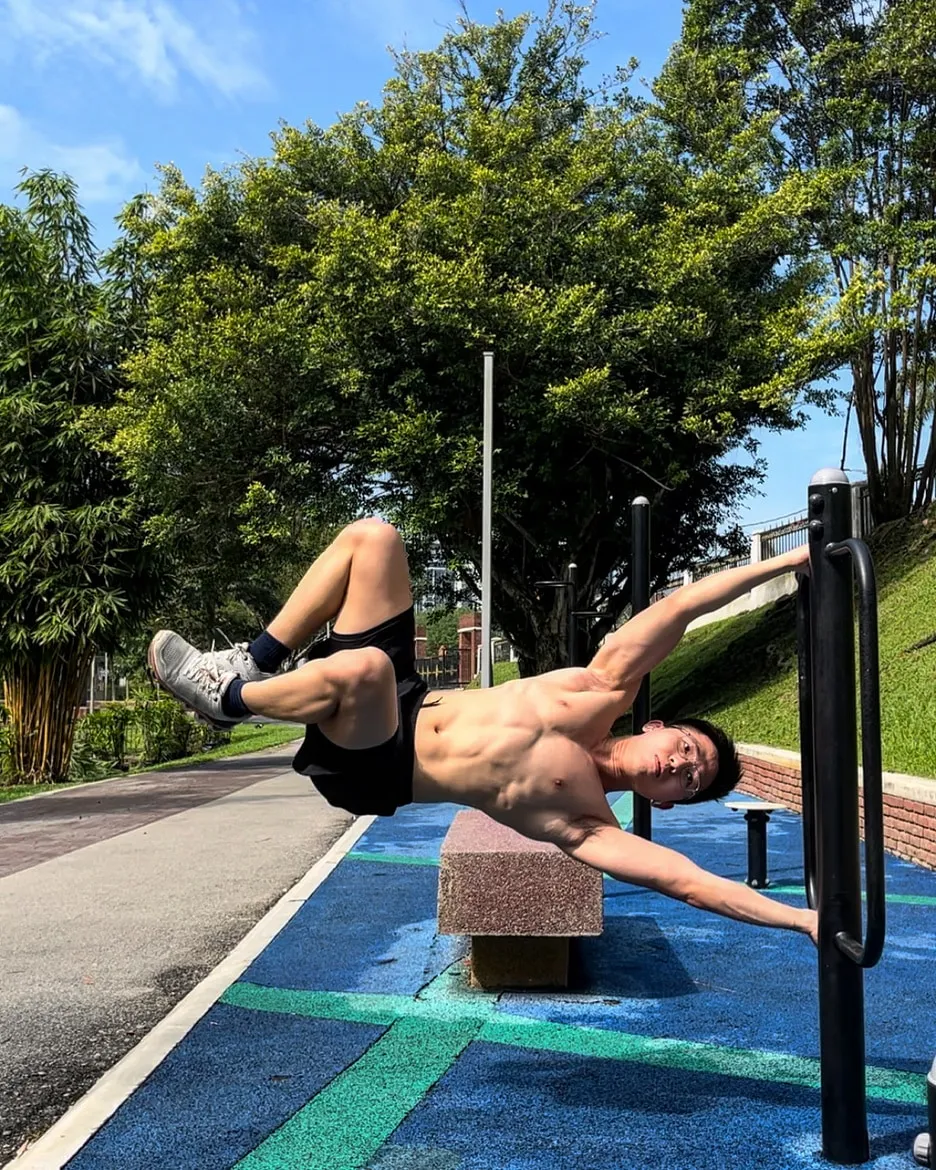 Jeremiah Lung holding a straddle planche on outdoor parallel bars